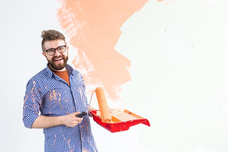 happy man painting interior wall with paint roller new house guy with roller applying paint 230311 12112.jpg