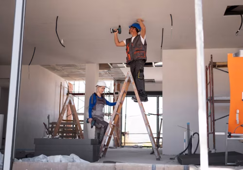 Handyman Services full shot man woman standing ladder ceiling & wall maintenance